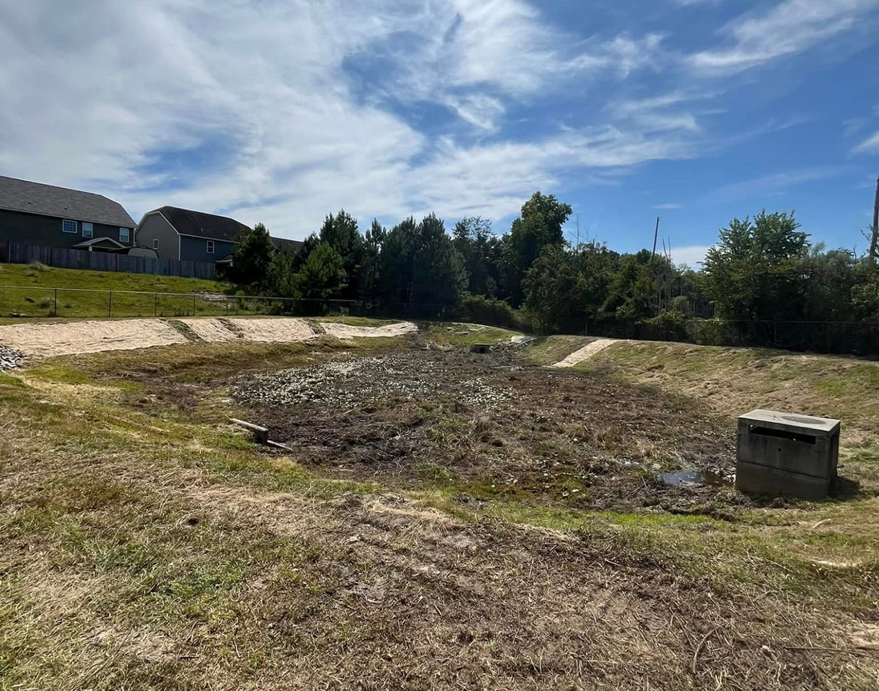  Cleared retention pond in a neighborhood showing cleaned banks and partially drained water